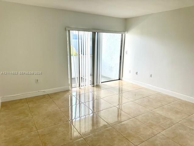 Interior space featuring large-format neutral tile flooring and sliding glass door with vertical blinds
