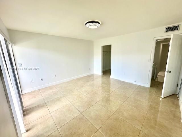 Neutral-toned tile flooring, flush-mount circular ceiling lighting, and smooth wall finish
