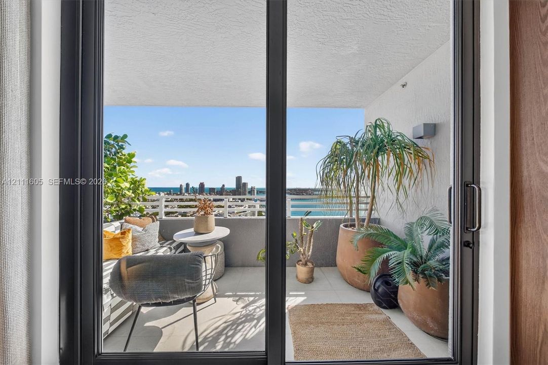 Covered balcony featuring black-framed sliding glass doors, neutral tile flooring, and white metal railings