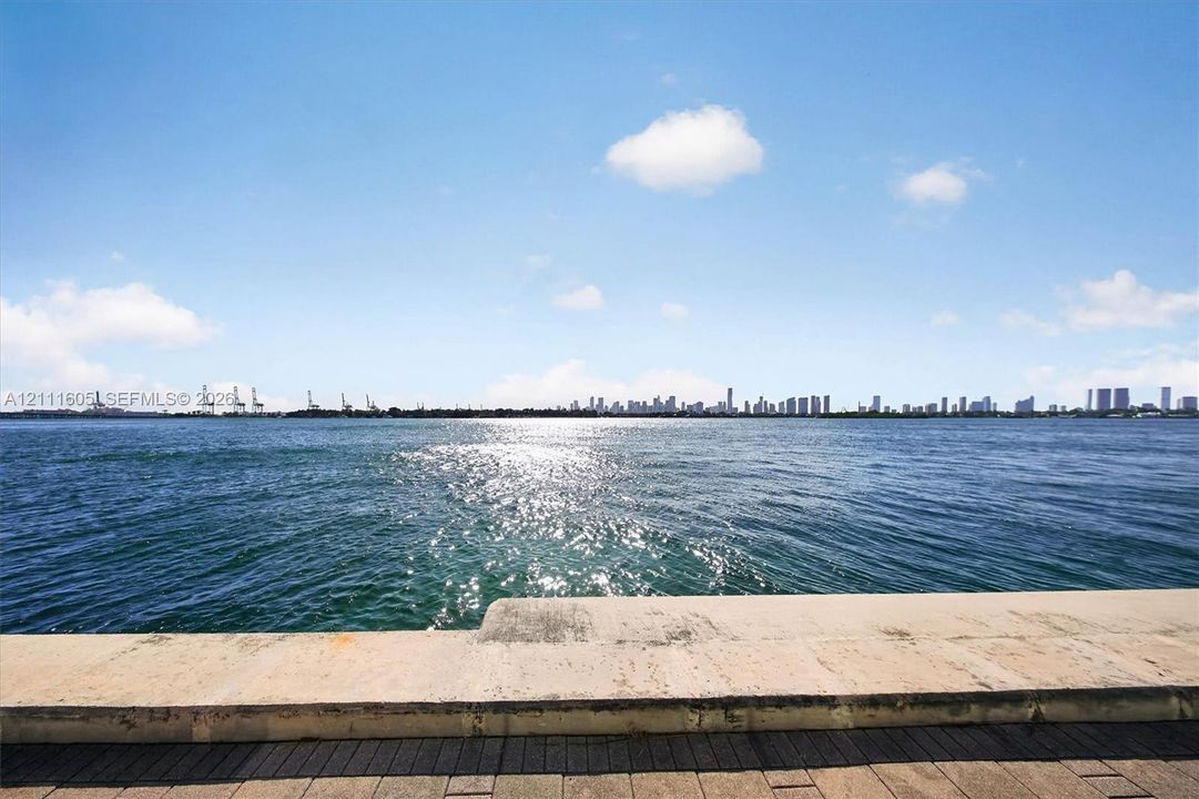 Waterfront property featuring a concrete seawall, stone-paver hardscaping, and a skyline horizon