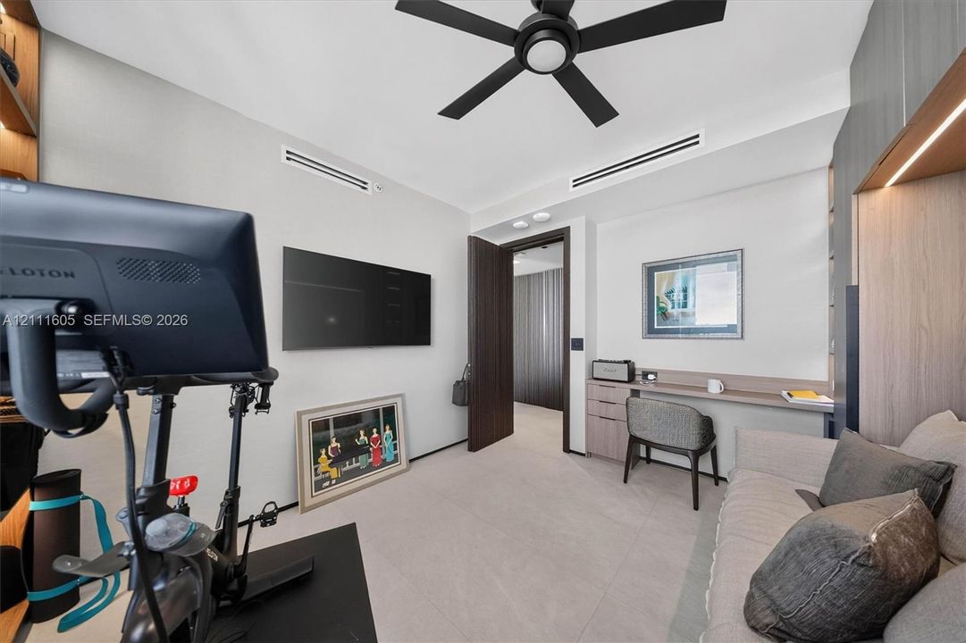Neutral-toned flooring, built-in desk with integrated storage cabinetry, recessed ceiling lighting, and matte black ceiling fan