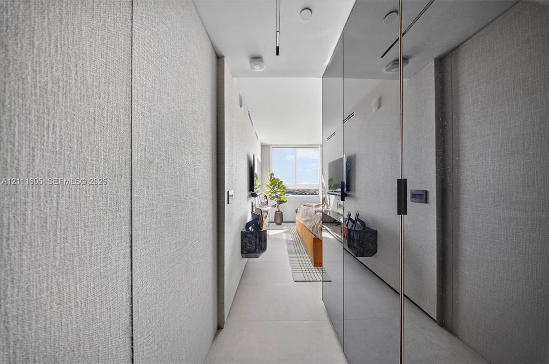 Full-height wall panels with textured light-gray finish, floor-to-ceiling mirror-finish cabinetry, porcelain tile flooring, and integrated ceiling track lighting