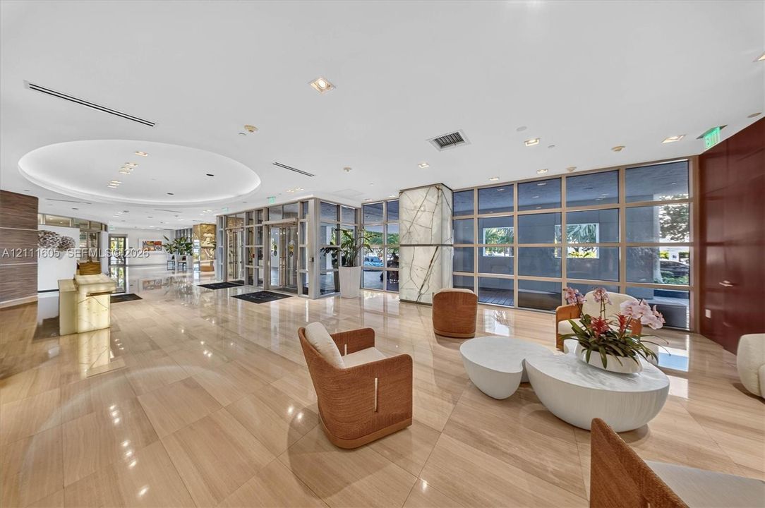 Lobby featuring polished stone flooring, recessed circular ceiling lighting, floor-to-ceiling glass panel walls, and a feature pillar with stone cladding