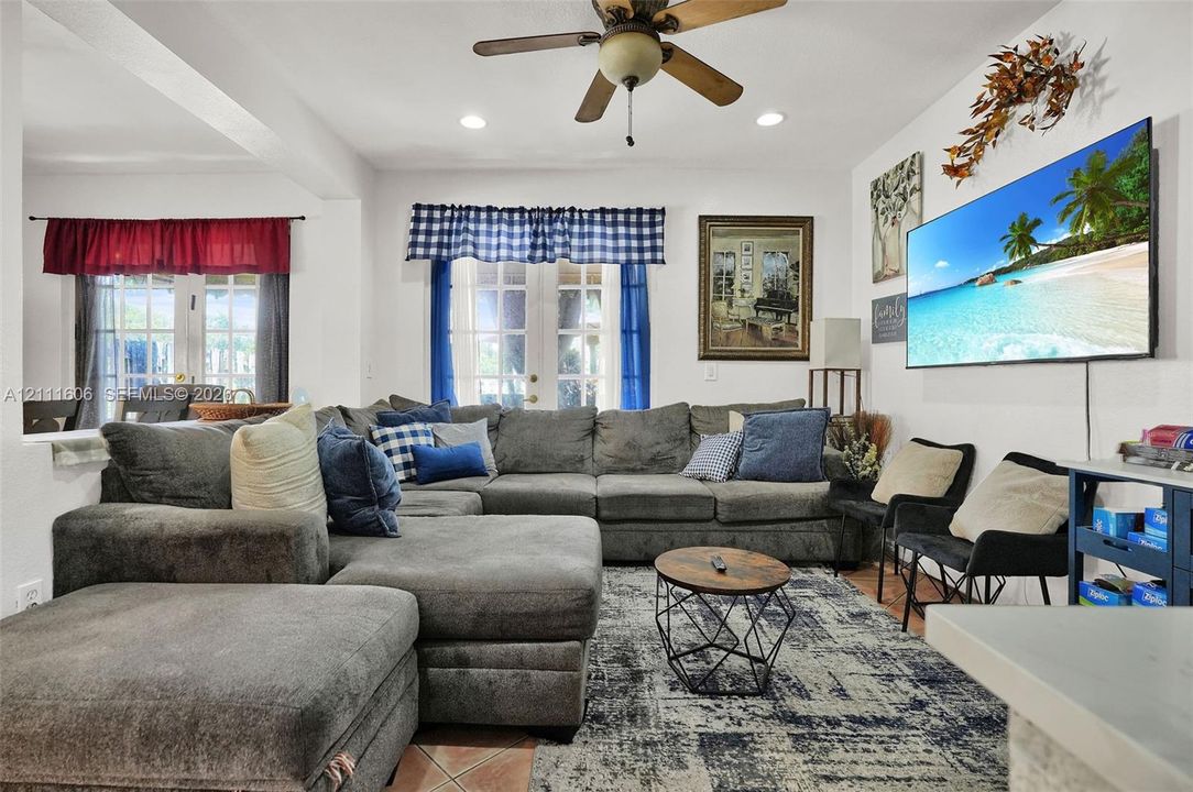 Living area featuring tile flooring, ceiling fan, recessed lighting, and dual sets of French doors