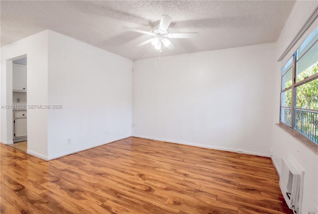 Living space featuring wood-finish flooring, a ceiling-mounted light fixture with a fan, and expansive windows