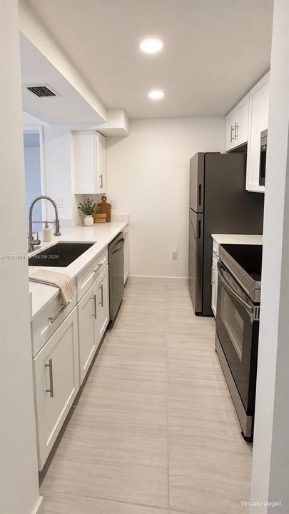 Modern kitchen featuring sleek white cabinetry, elegant quartz countertops, recessed ceiling lighting, and brand new stainless steel appliances.