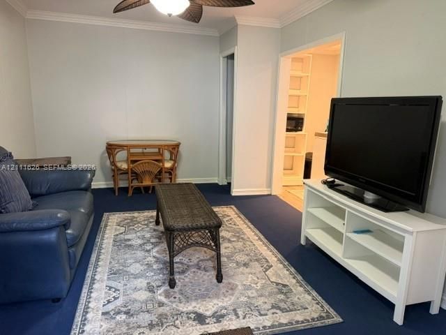Room featuring crown molding, a ceiling fan with palm-leaf style blades, and built-in wall shelving