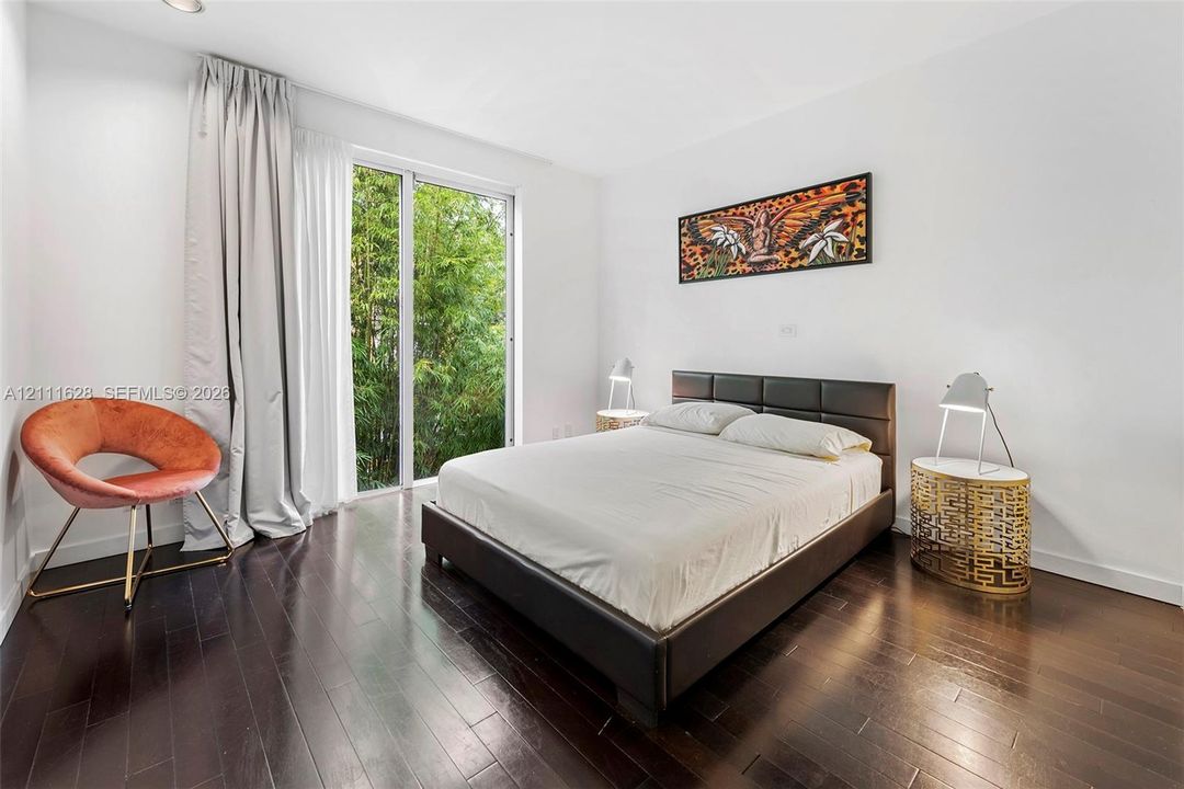 Dark-toned wood-finish flooring, floor-to-ceiling glass door, and neutral wall palette