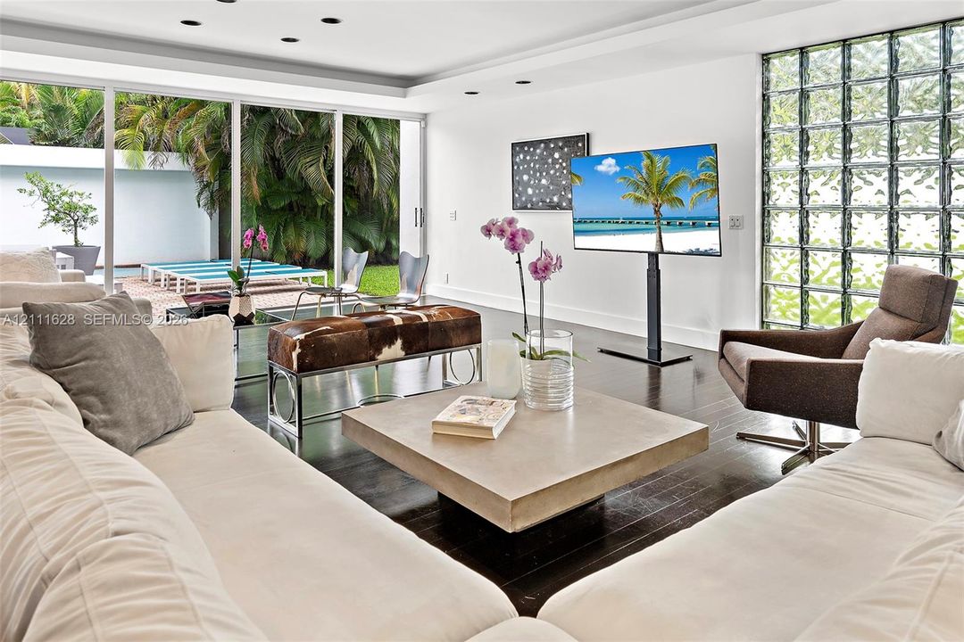 Floor-to-ceiling glass walls, glass block accent wall, recessed lighting, and wood-finish flooring