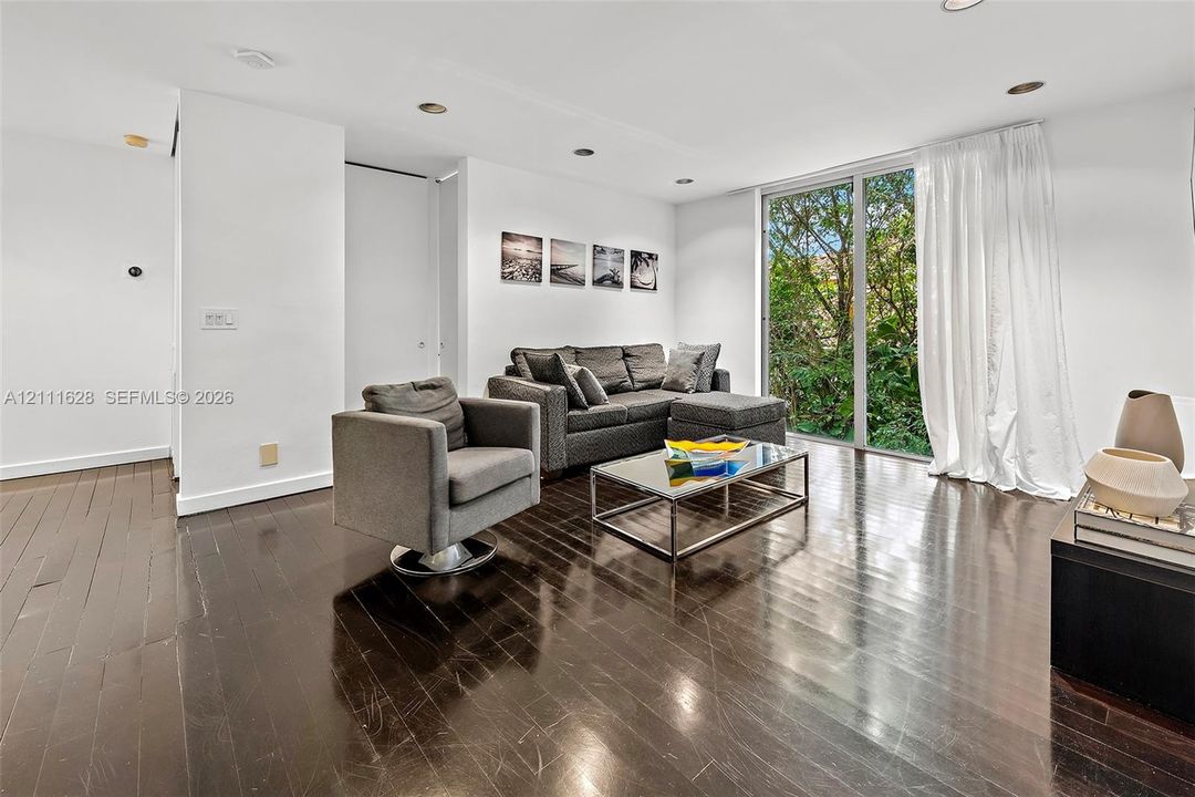 Dark-stained wood-finish flooring, recessed lighting, and floor-to-ceiling glass paneling providing natural light
