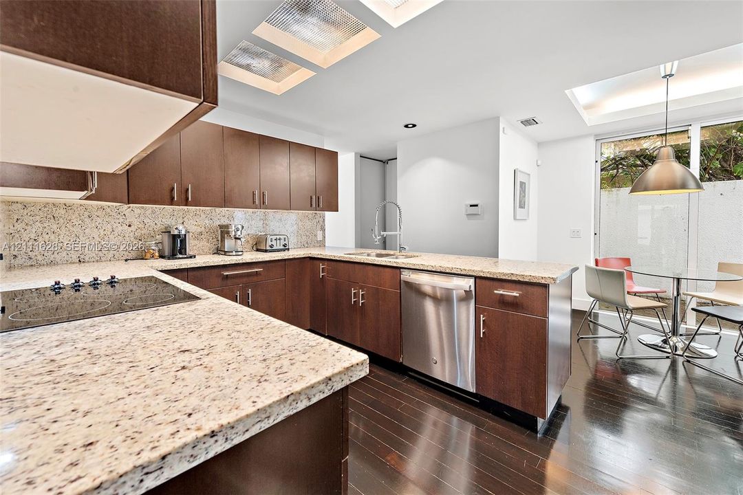 Kitchen featuring dark wood-finish cabinetry, stone countertops, stainless steel appliances, dark wood-finish flooring, and recessed ceiling panels