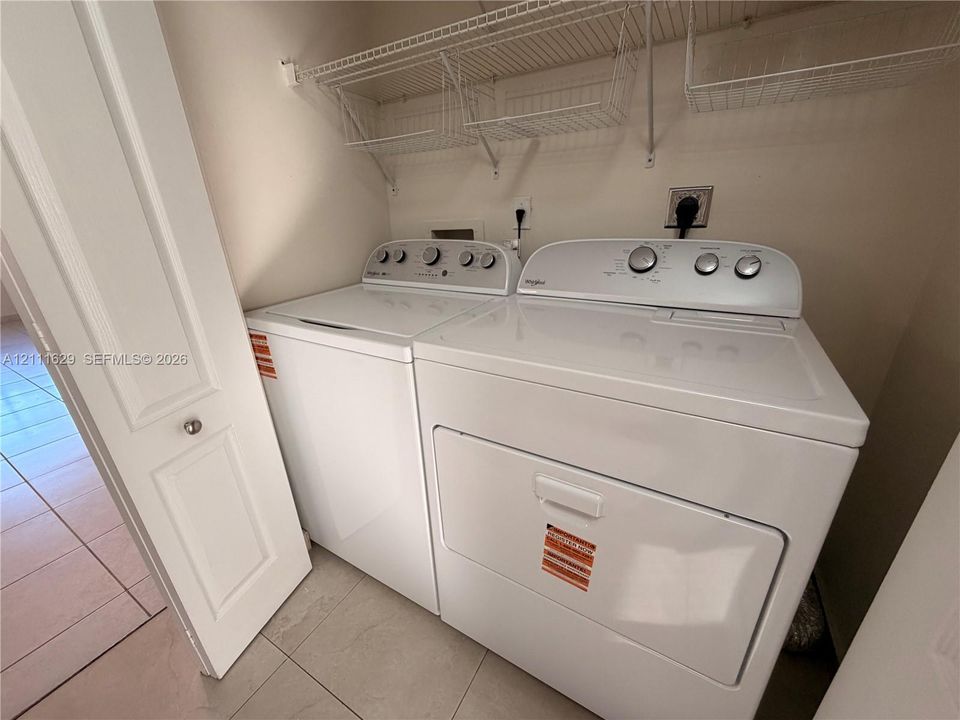 Laundry closet featuring tile flooring, bi-fold door, and overhead wire shelving
