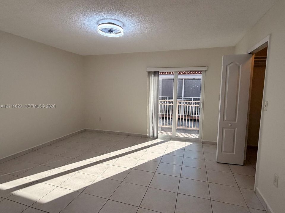 Ceramic tile flooring, flush-mount ceiling light fixture, sliding glass door, and a built-in closet with a panel door