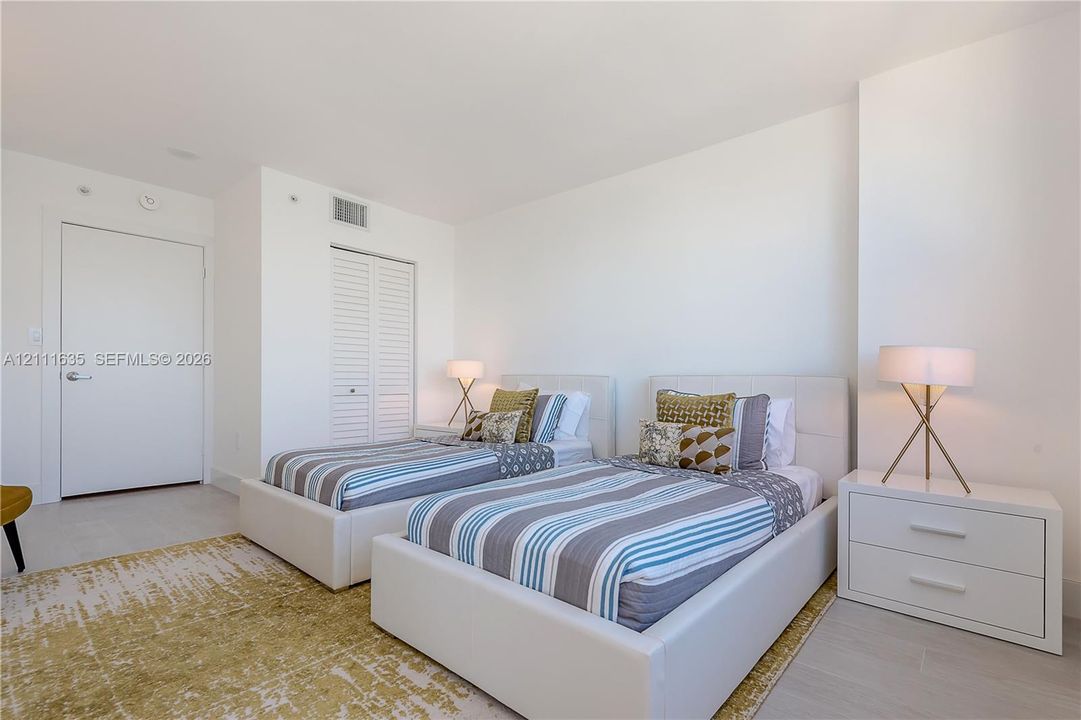 Neutral-toned interior featuring light wood-finish flooring, white walls, and a closet with louvered doors