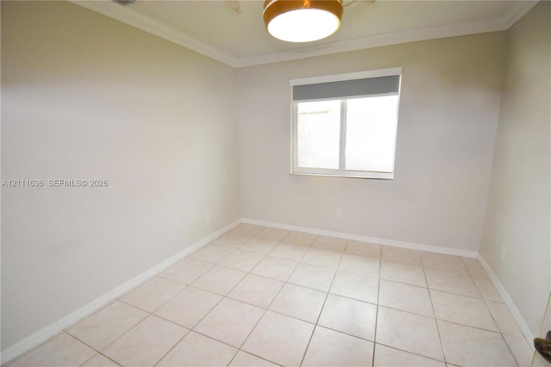 Neutral-toned interior featuring ceramic tile flooring, crown molding, and a central circular flush-mount ceiling light fixture