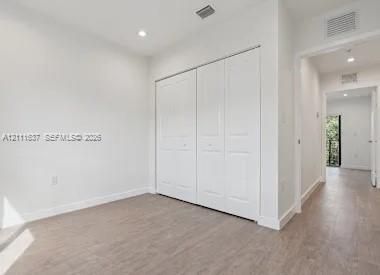 Neutral interior featuring wood-finish flooring, recessed lighting, and a double-door closet with paneled detailing