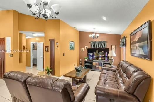 Living area featuring tile flooring, vaulted ceilings, and dual multi-arm chandeliers