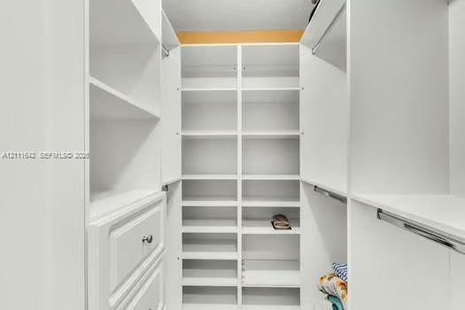 Custom white cabinetry featuring floor-to-ceiling shelving, built-in drawer storage, and integrated hanging rods