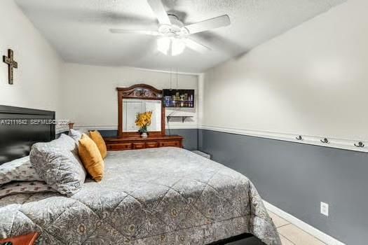 Neutral wall color scheme with chair rail molding, ceiling-mounted light fixture with fan, and wall-mounted storage hooks