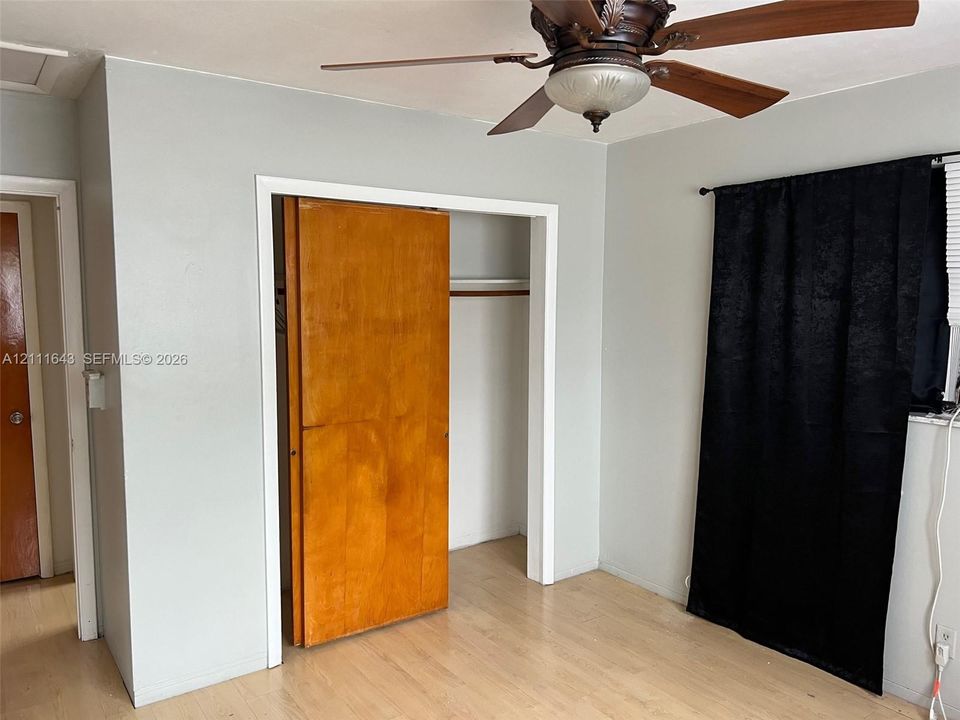Wood-finish flooring, ceiling fan with integrated lighting, and natural wood closet door