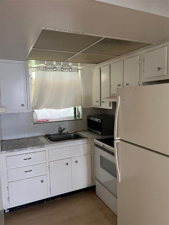 Kitchen featuring white cabinetry, stone-finish countertops, an undermount stainless steel sink, and wood-finish flooring