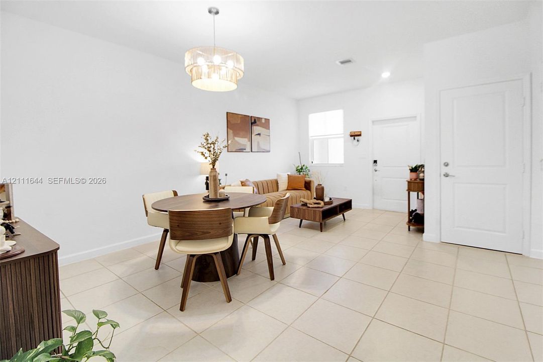 Large-format tile flooring, drum-style chandelier with metallic finish, crisp white wall palette, and six-panel interior door
