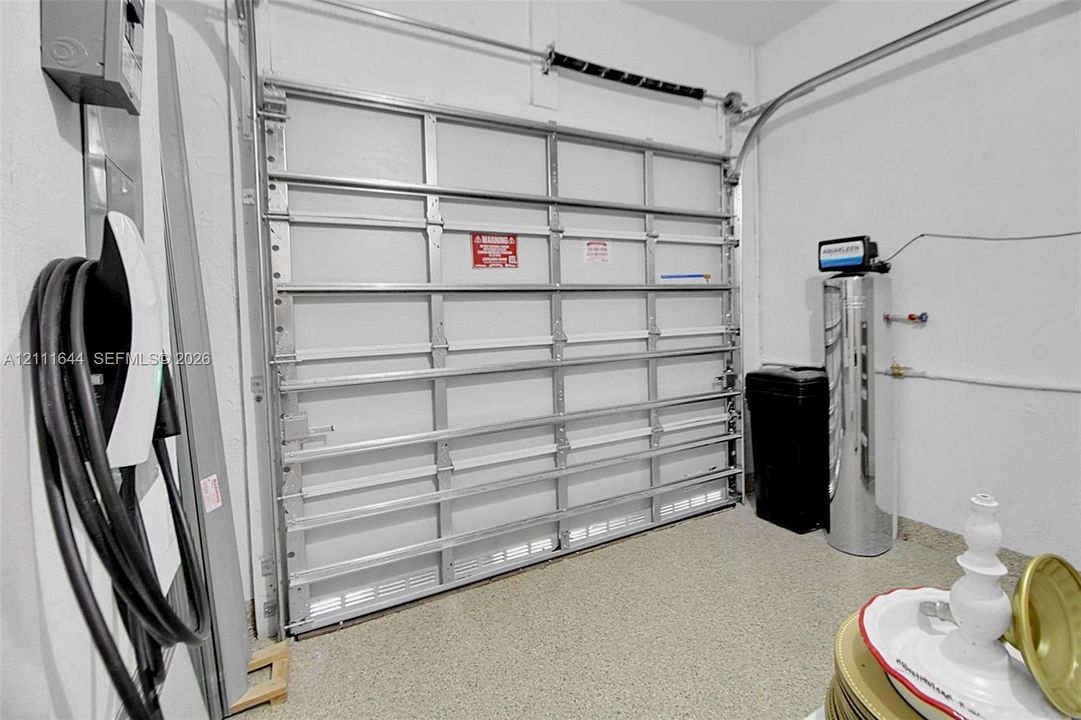 Attached electric vehicle charging station, overhead metal garage door, epoxy-coated flooring, and installed water filtration system