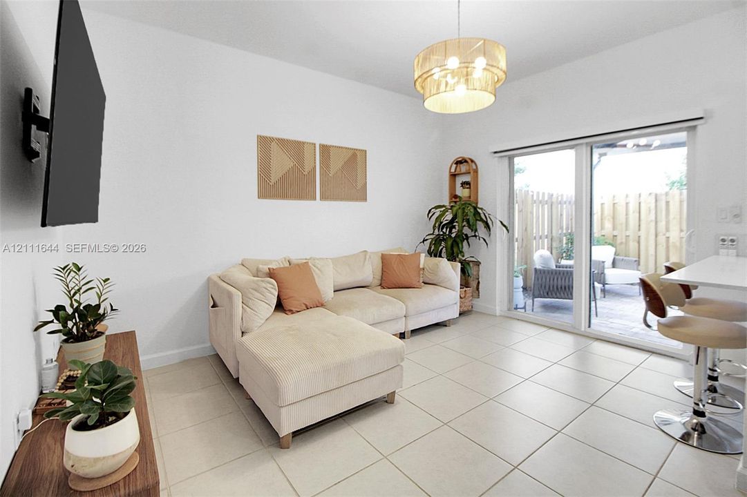 Neutral tile flooring, tiered drum pendant lighting, and a large sliding glass door featuring integrated patio access