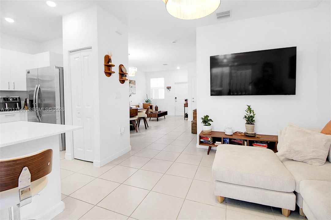 Open-concept floor plan featuring large-format tile flooring, white cabinetry, integrated stainless steel appliances, and recessed lighting