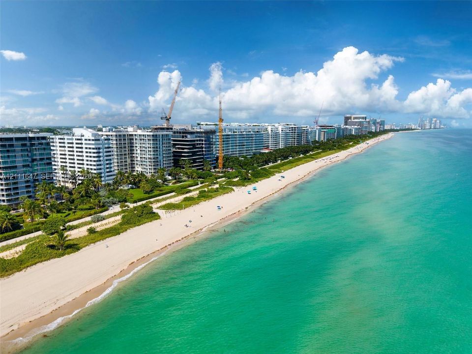 Aerial perspective of coastal multi-unit residential architecture featuring direct beach access, sand shoreline, and ocean frontage