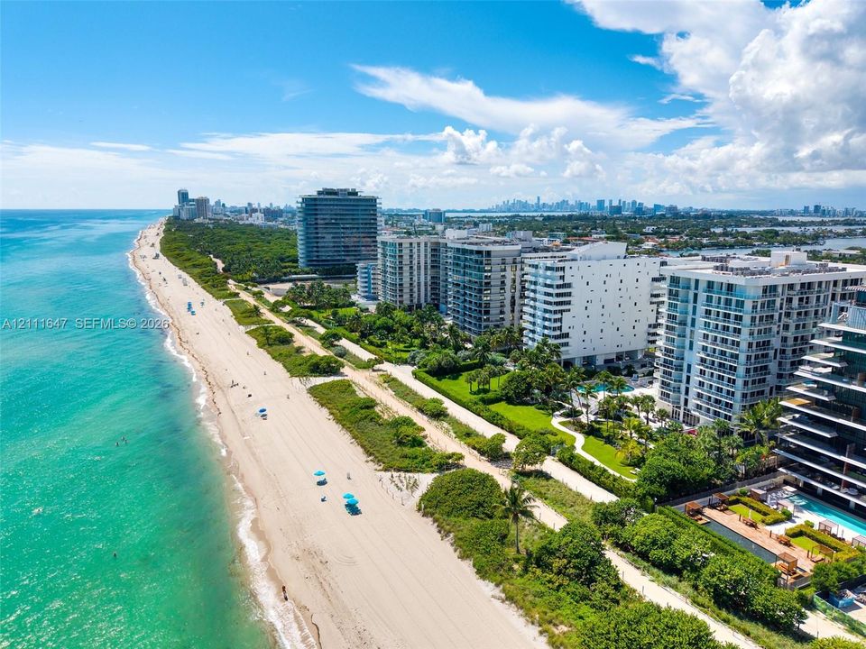 Coastal aerial perspective featuring direct oceanfront access, pristine sandy shoreline, and proximity to expansive waterfront high-rise development
