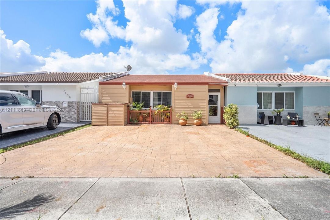 Exterior featuring a stamped concrete driveway, low-profile horizontal siding, tile roof, and a private enclosed front patio with integrated railing