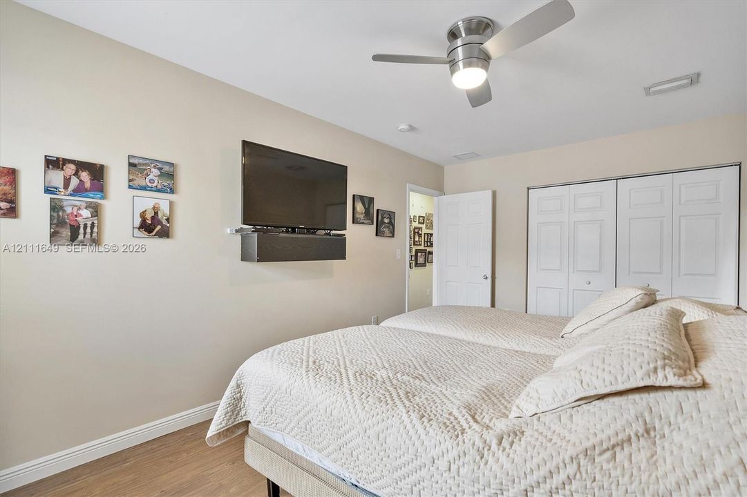 Room featuring wood-finish flooring, a ceiling fan with integrated lighting, and a white bifold closet