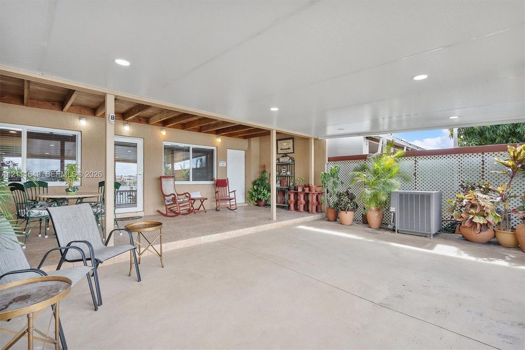Covered patio featuring an expansive concrete surface, recessed lighting, exposed wood ceiling beams, and decorative lattice wall paneling