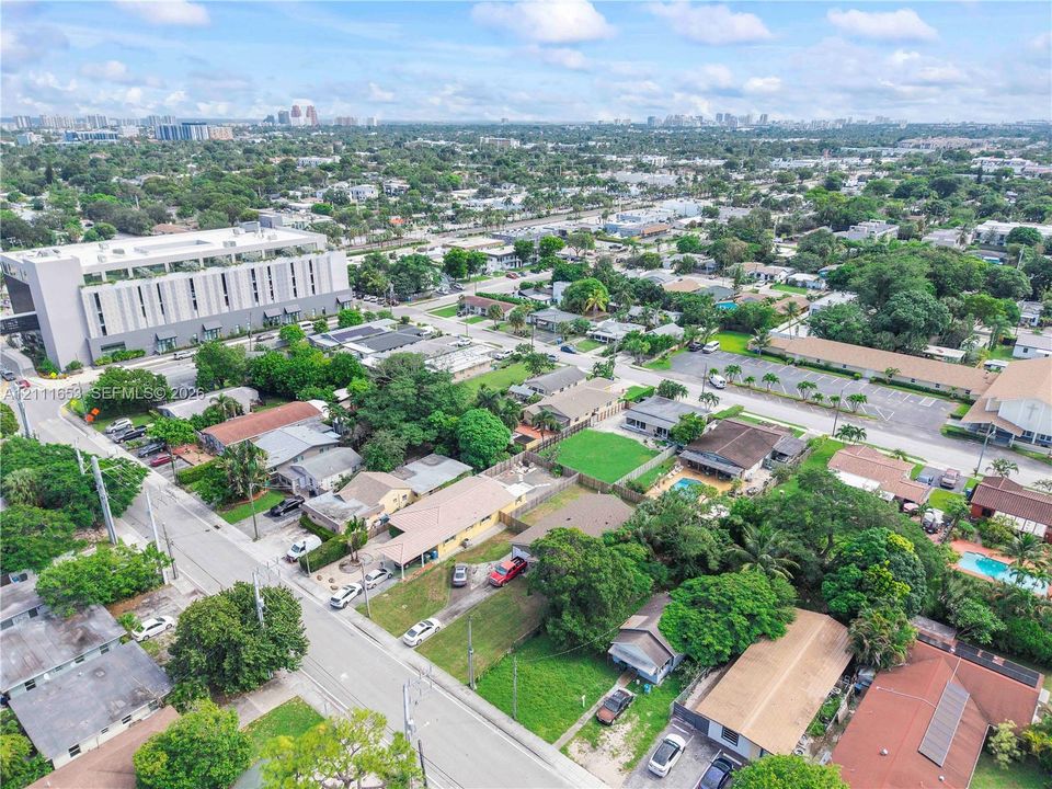 Aerial perspective featuring established residential surroundings with mature trees, expansive green lawns, and diverse roofline configurations
