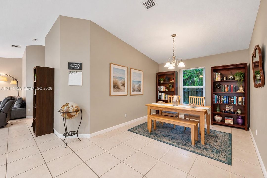 Neutral-toned interior featuring ceramic tile flooring, vaulted ceilings, and a decorative multi-arm chandelier