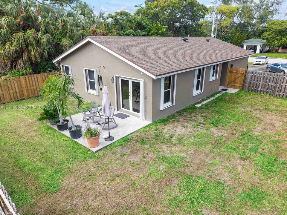 Paved backyard patio, double glass doors, and wood-panel perimeter fencing