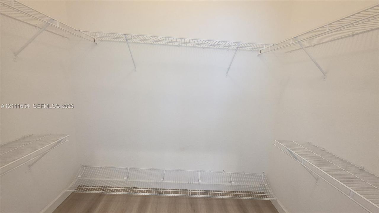 Walk-in closet featuring white wire shelving and wood-finish flooring