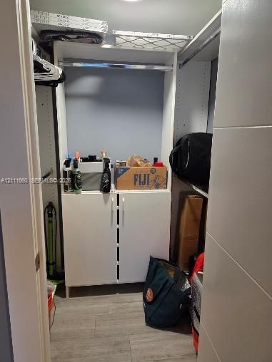 Built-in white storage cabinetry, wood-finish flooring, and integrated metal clothing rods