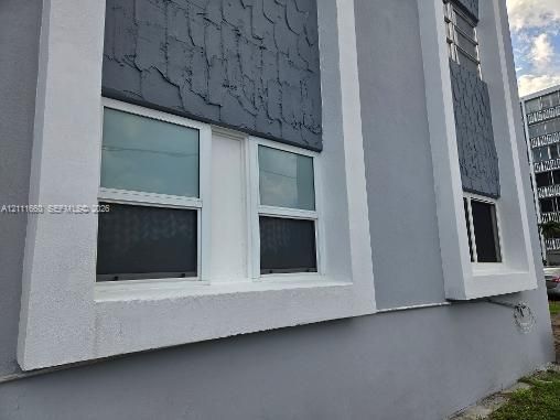 Exterior facade featuring smooth stucco finishes, decorative textured panels, and deep-set window frames with contrast trim