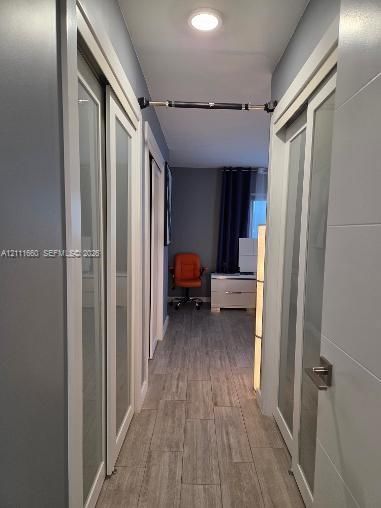 Hallway featuring ceramic-finish tile flooring, recessed ceiling lighting, and sliding doors with glass panel inserts