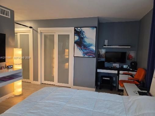 Sliding glass-panel closet doors, built-in desk with overhead shelving, and light-toned flooring