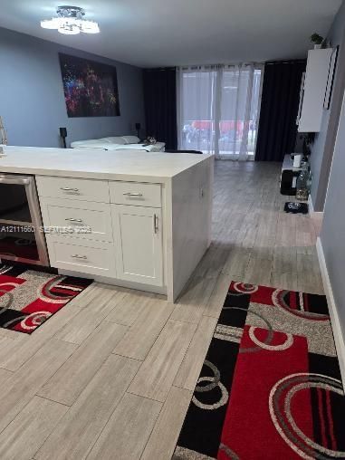 Kitchen island featuring white cabinetry, metallic hardware, and a solid-surface countertop with an integrated dishwasher