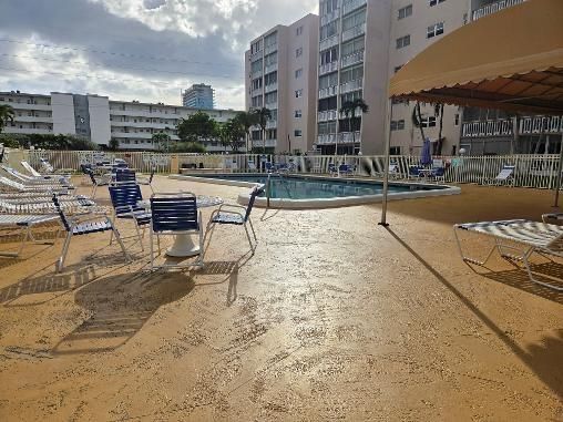In-ground swimming pool featuring a textured pool deck and a permanent shaded pergola structure