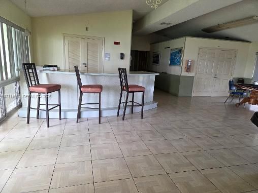 Built-in wet bar with a raised counter, tile flooring, and double-door entryways
