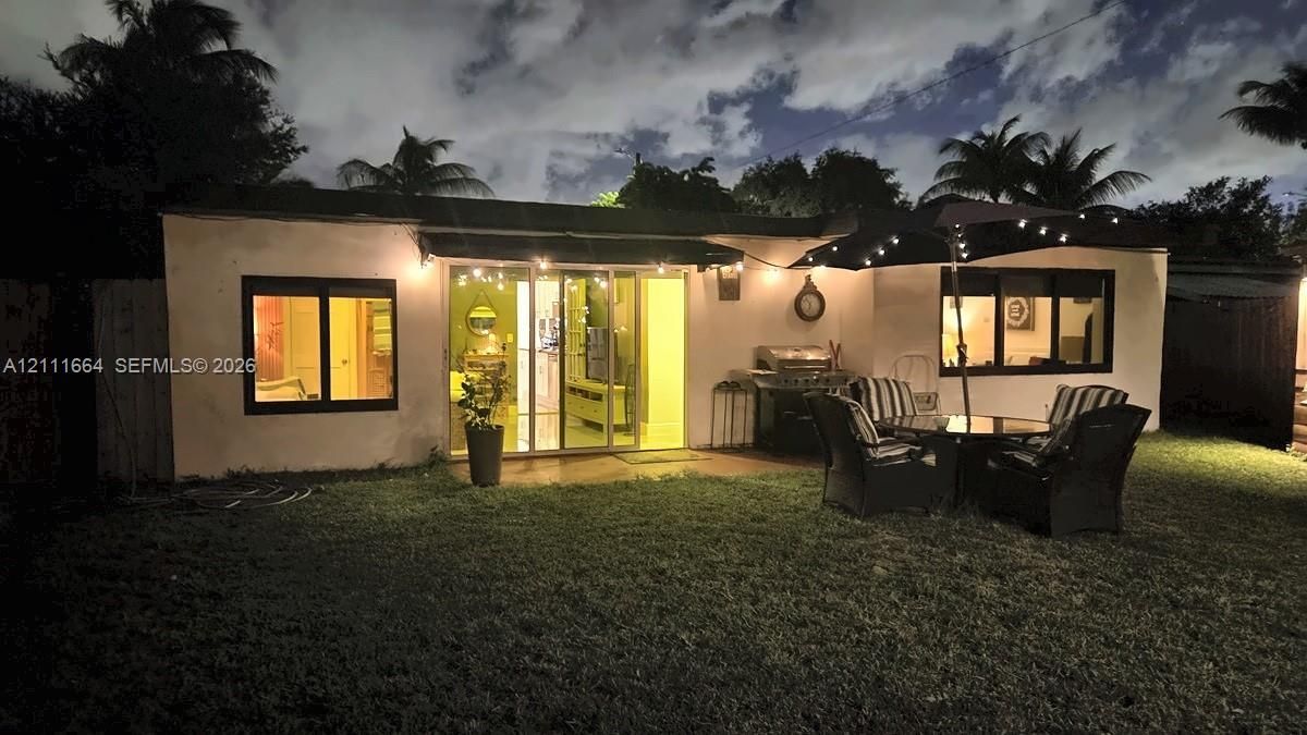 Rear exterior featuring a sliding glass door, dark-framed windows, and an expansive lawn