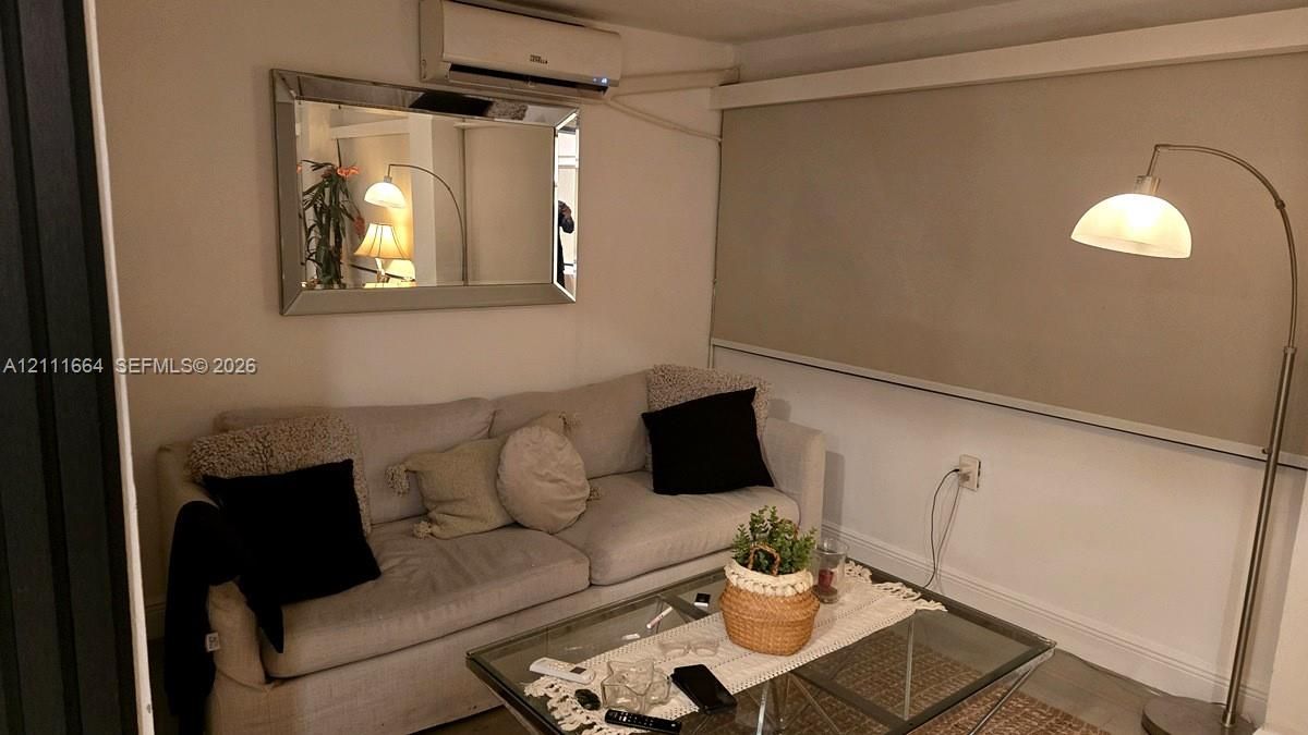 Wall-mounted ductless air conditioning unit, rectangular wall mirror with a beveled frame, and wide-format roller window shade