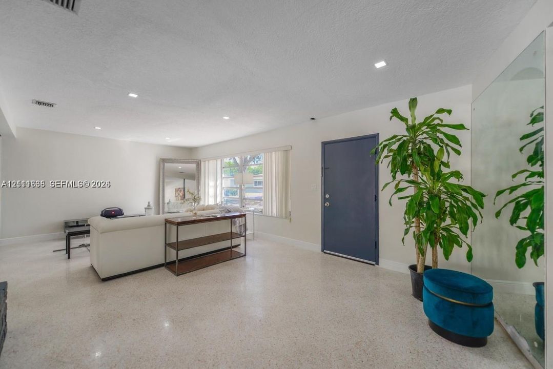Interior space featuring polished terrazzo flooring, recessed lighting, and a large wall-mounted mirror panel