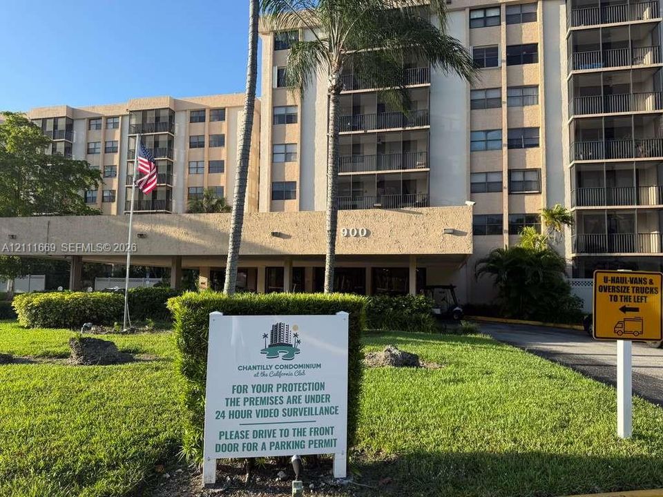 Multi-story residential building exterior featuring a covered porte-cochère, private screened-in balconies, and mature landscaping