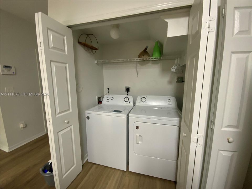 Dedicated laundry area featuring a wire storage shelf, ceiling-mounted lighting, and dual bifold doors